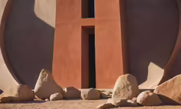 an adobe - style house with a window between two large stones