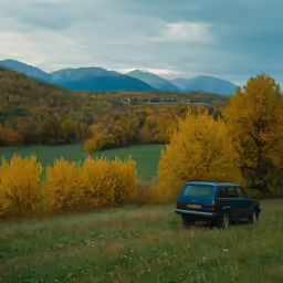 a suv sits in the grass and next to mountains
