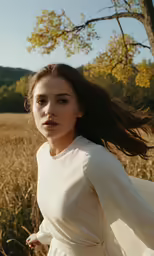 a beautiful young woman in a white dress stands in the middle of a field