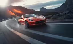 the rear of a red sports car on a mountain road