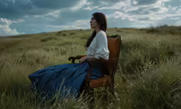 a woman in blue skirt sitting on brown chair