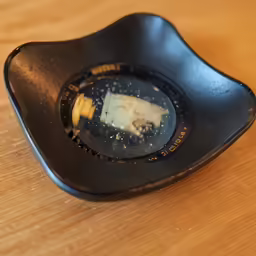 a piece of cheese in an upside down black plate
