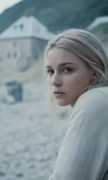 a beautiful blonde haired woman standing on the beach