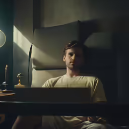 a man in the bedroom under a lamp