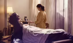 the girl is looking at a man sitting on a bed