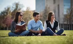 a man and a woman sitting on the ground together while reading