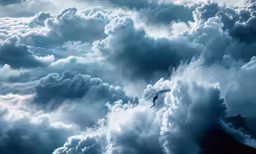 a person flying through the cloudy sky above mountains