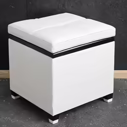 a white leather ottoman is sitting in front of a wall