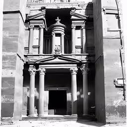 a large building has four pillars and two clock at the top