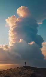 a person standing on top of a hill under a large cloud