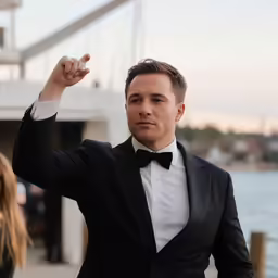 the man in a tuxedo is pointing at something
