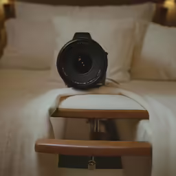 a large lens is sitting on a stool at the end of the bed