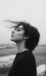 a woman looking up to the sky while her hair is blowing in the wind