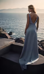 a woman looking out over water, standing on stairs