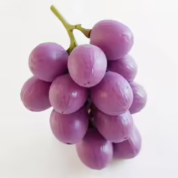 a bunch of grapes sit on a white table