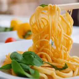 a close up of a bowl of spaghetti being stirred with a wooden spoon