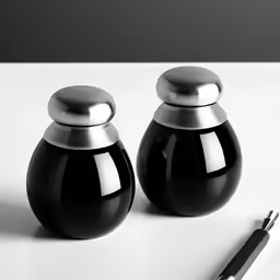 two black salt and pepper shakers sitting on top of a counter