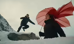 two people jumping in the air while holding open umbrellas