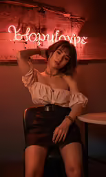 an asian woman sits at a table and poses for the camera