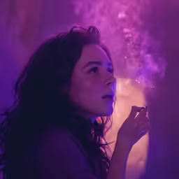 a woman in a dark room is lit by light