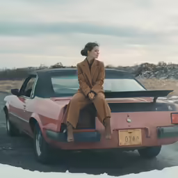 a woman sitting on the hood of a car