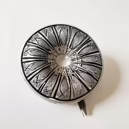 a round decorative silver object on a white surface