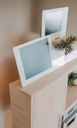 an ipad on top of a wooden cabinet
