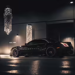 a black sports car parked in front of a modern light sculpture