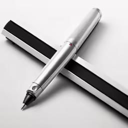 the silver and black pen is laying on the desk