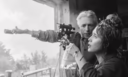 man shooting another woman in front of a building with snow