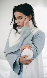 a woman is holding her shoulder while she looks down