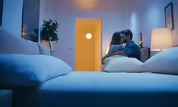 a man kissing a woman through the bed with pillows