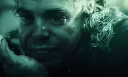 an old man with white hair and curly hair on his face holding his hand up to the side