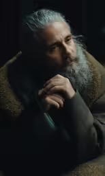 a man with grey hair and a beard in a black coat