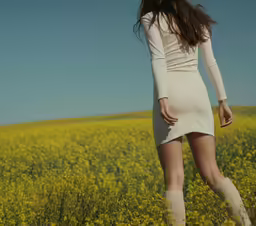 a woman walking through the middle of a field of flowers