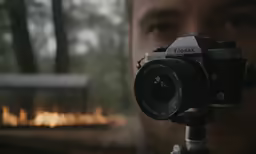 a man standing in front of a fire holding a camera