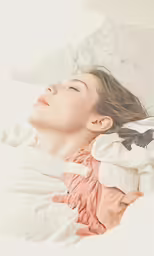 a woman laying on top of a bed under white sheets
