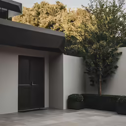 two planters next to the entrance to a large white home