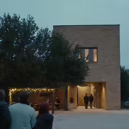 people walk outside in a large brick building at night