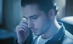 a man holding his hand to his ear looking away