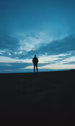 the man stands alone in front of the sky as the sun sets