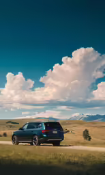 a black suv parked in the middle of a grassy field
