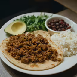 a plate with a taco and rice next to two different types of beans