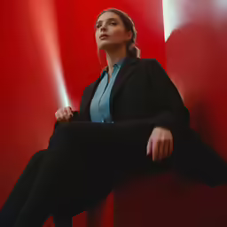 a lady with a black jacket sitting next to red columns