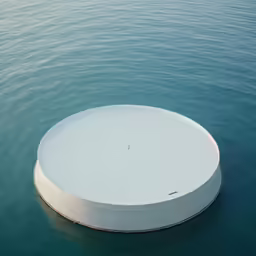 large round structure floating on water with blue sky in background