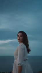 an attractive young woman standing on the beach near the ocean