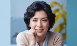 an asian woman wearing a light blue shirt sitting and smiling