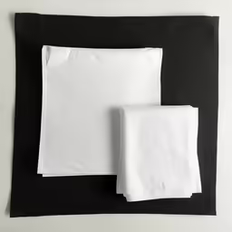 folded and unfolded towels are on top of black paper