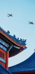 four jets fly overhead over chinese roof