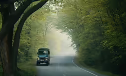 truck coming down the road in a wooded area